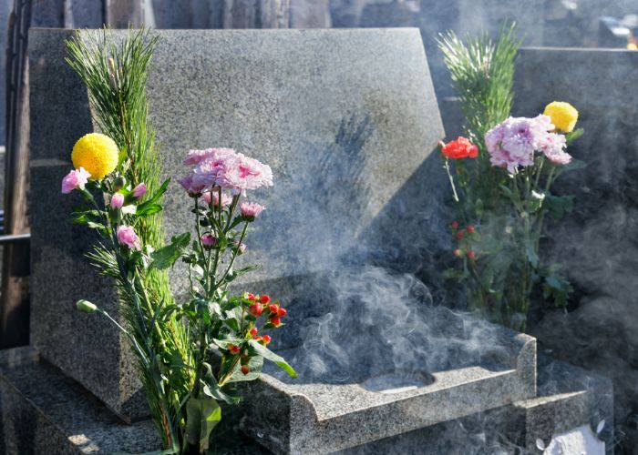 A freshly cleaned grave has been left offerings of incense and fresh flowers.